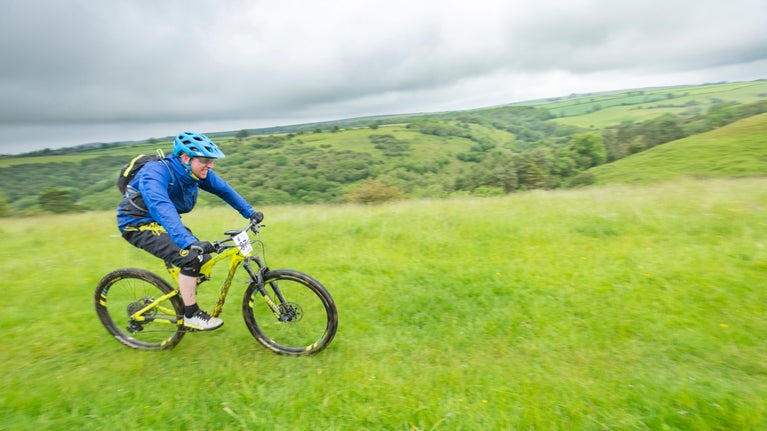 A cyclist riding across a grassy landscape